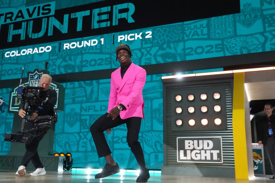 Travis Hunter, in a pink suit, celebrating being drafted.