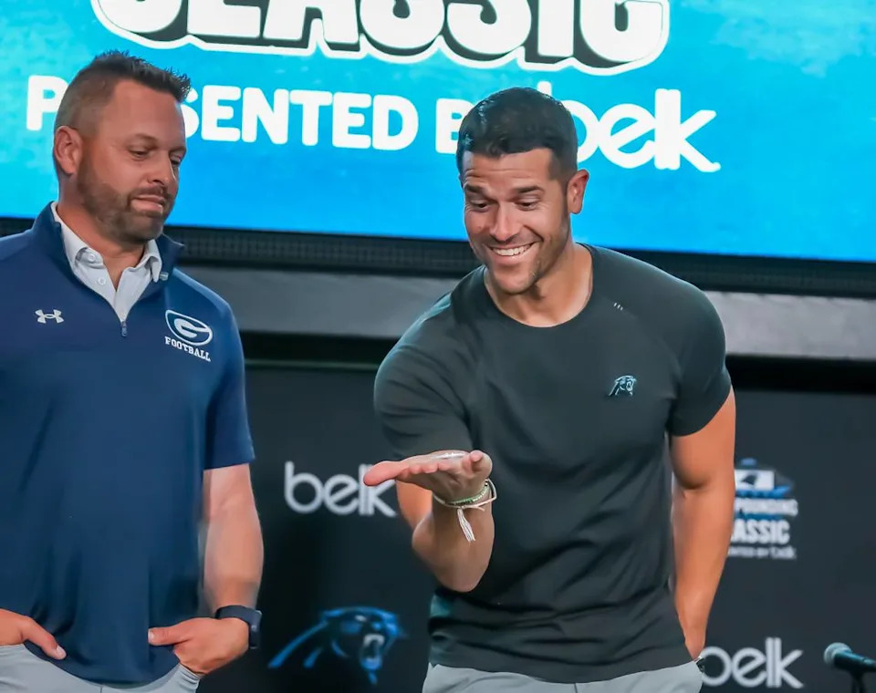 Greensboro Grimsley coach Darryl Brown watches on as Carolina Panthers’ coach Dave Canales performs a ceremonial coin toss during media day for the Keep Pounding High School Classic Wednesday, May 7, 2025 Kelly Hood/Special to The Observer