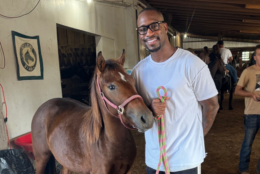 Former Washington Commander Vernon Davis stands with a horse