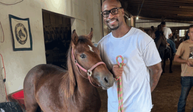Former Washington Commander Vernon Davis stands with a horse