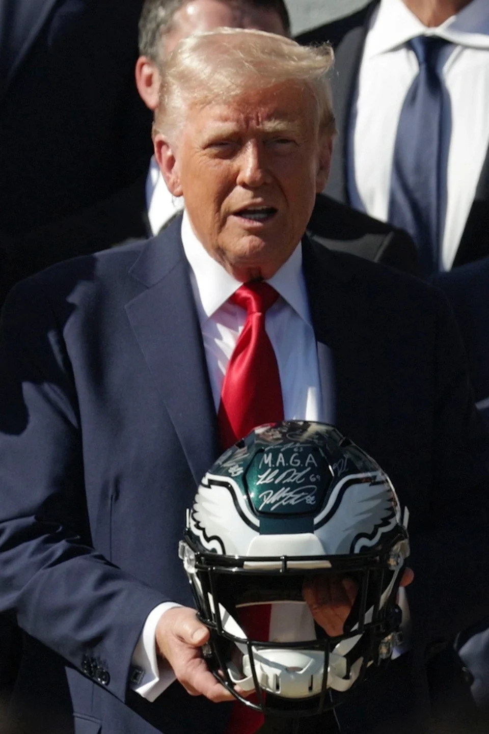 Trump holding an NFL Philadelphia Eagles helmet during an event