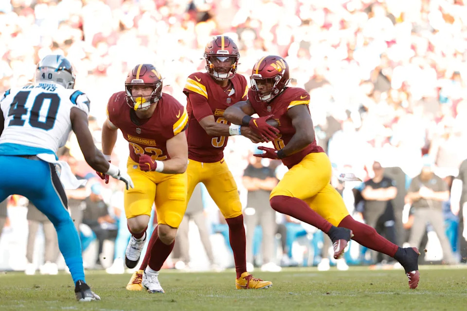 Washington Commanders quarterback Jayden Daniels (5) hands the ball to Commanders running back Brian Robinson Jr. (8) during the first quarter against the Carolina Panthers at Northwest Stadium.© Amber Searls-Imagn Images