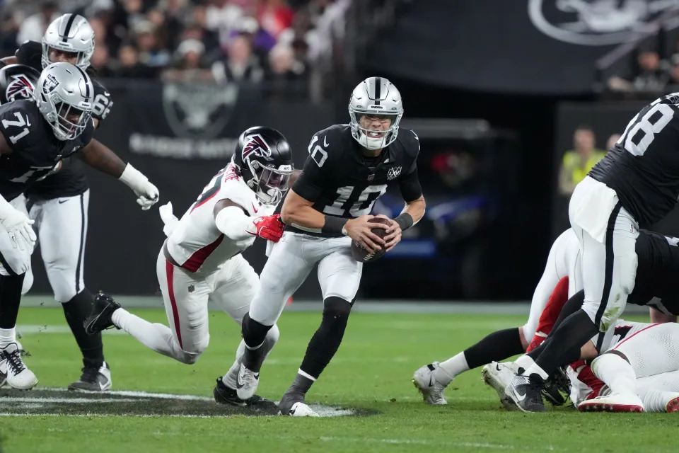 Dec 16, 2024; Paradise, Nevada, USA; Las Vegas Raiders quarterback Desmond Ridder (10) carries the ball against Atlanta Falcons linebacker Arnold Ebiketie (17) in the first half at Allegiant Stadium. Mandatory Credit: Kirby Lee-Imagn Images