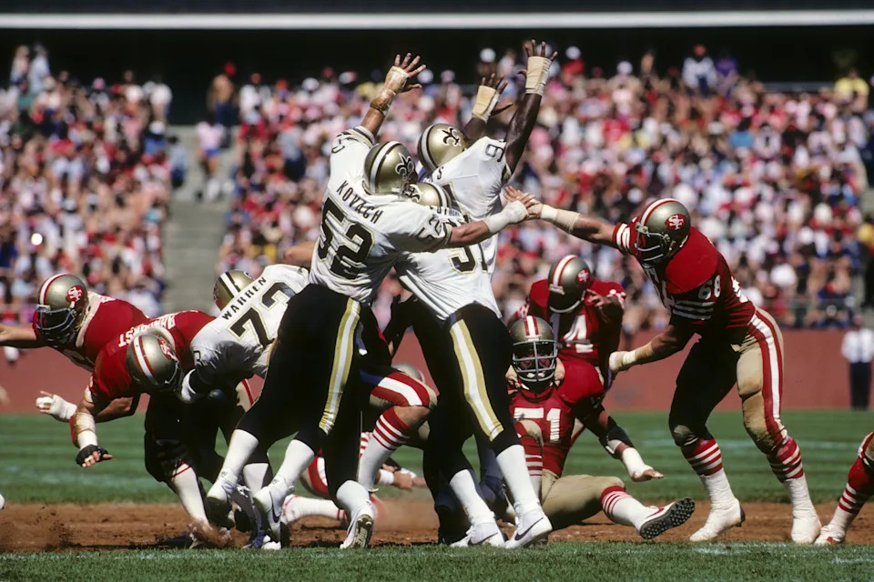 SAN FRANCISCO - SEPTEMBER 16: Linebacker Jim Kovach #52 and defensive end Jim Wilks #94 of the New Orleans Saints attempt to block a kick by Ray Wersching #14 of the San Francisco 49ers during a game at Candlestick Park on September 16, 1984 in San Francisco, California. The 49ers won 30-20. (Photo by George Rose/Getty Images)