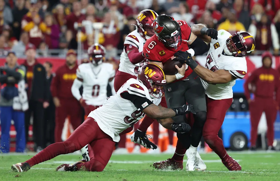 Jan 12, 2025; Tampa, Florida, USA; Tampa Bay Buccaneers quarterback Baker Mayfield (6) runs against Washington Commanders defensive end Dorance Armstrong (92) and linebacker Bobby Wagner (54) during the second quarter of a NFC wild card playoff at Raymond James Stadium. Mandatory Credit: Kim Klement Neitzel-Imagn Images