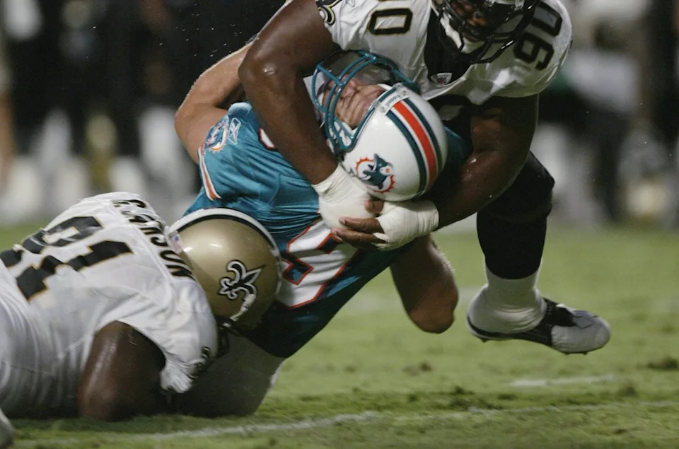 MIAMI - AUGUST 15: Defensive tackles Kenny Smith #90 and Grady Jackson #91 of the New Orleans Saints crush quarterback Jay Fiedler #9 of the Miami Dolphins during the NFL preseason game on August 15, 2002 at Pro Player Stadium in Miami, Florida. The Saints won 24-7. (Photo By Eliot J. Schechter/Getty Images)