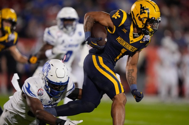West Virginia running back Jahiem White (1) runs from Memphis linebacker Elijah Herring (31) during the first half of the Frisco Bowl NCAA college football game Tuesday, Dec. 17, 2024, in Frisco, Texas. (AP Photo/LM Otero)