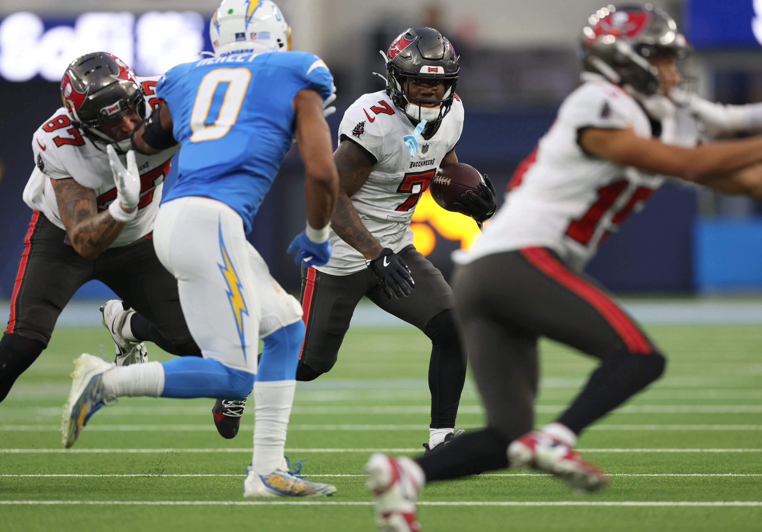 Bucky Irving of the Tampa Bay Buccaneers carries the ball in front of Daiyan Henley of the Los Angeles Chargers during a 40-17 win over the Chargers at SoFi Stadium on December 15, 2024 in Inglewood, California.