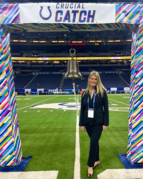 Spitznogle stands next to a bell with a sign saying "Crucial Catch" above her.