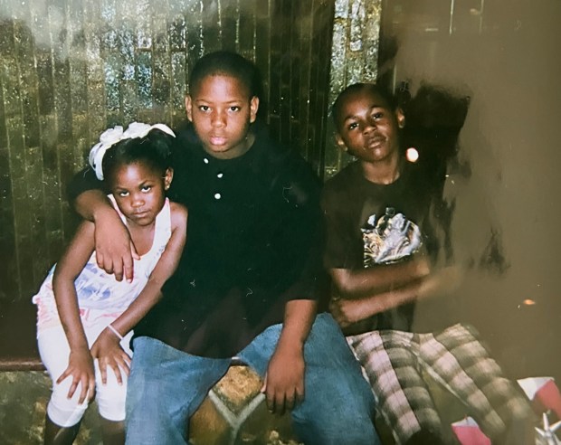 A young Que Robinson, right, sits with his cousin Aikeem, center, and sister Tiyana in an undated family photo. (Photo courtesy of Raheem Collier)