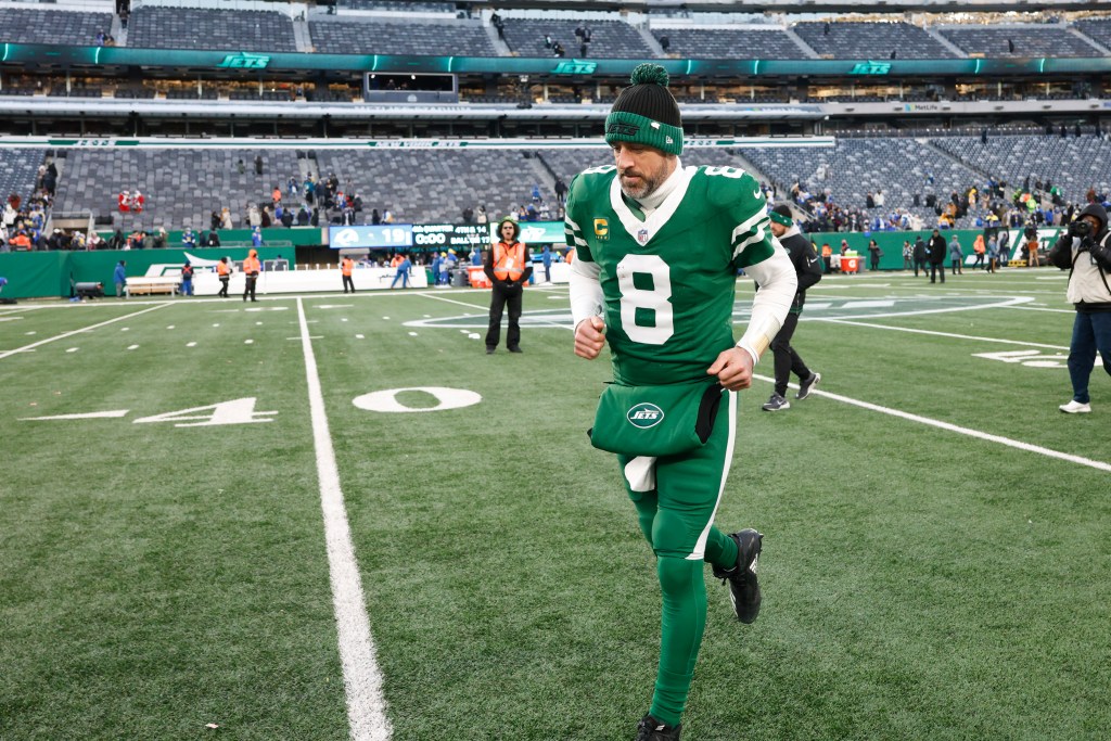 Aaron Rodgers in a New York Jets uniform on a football field.