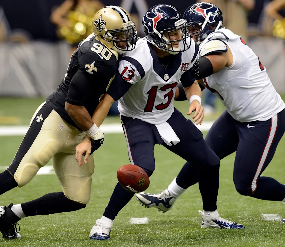 Aug 25, 2012; New Orleans, LA, USA; New Orleans Saints defensive end Turk McBride (90) knocks the ball out of the arm of Houston Texans quarterback T.J. Yates (13) during second half of their preseason game at the Mercedes-Benz Superdome. The Saints defeated the Texans 34-27. Mandatory Credit: John David Mercer-USA TODAY Sports