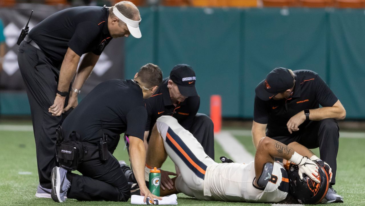 Oregon State medical trainers check the right knee of linebacker Matthew Tago (8) during the second half of an NCAA college football game against Hawaii, Saturday, Sept. 7, 2019, in Honolulu.