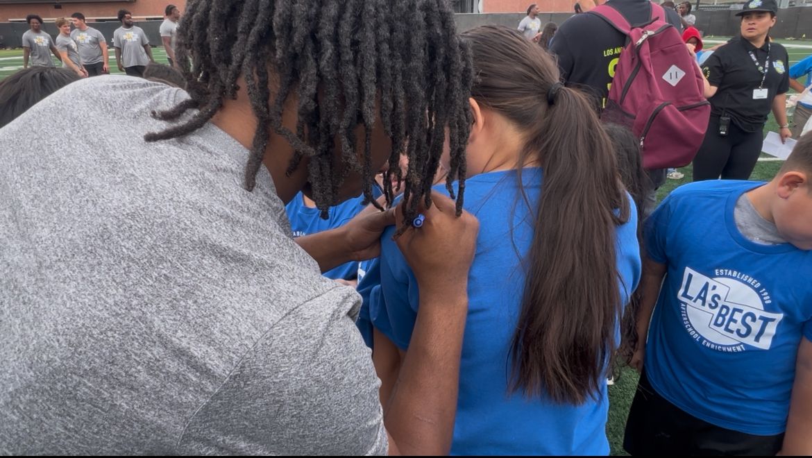 A USC football player signs a young student's shirt