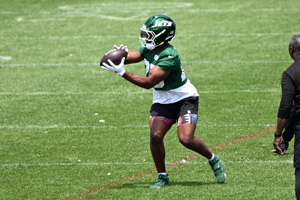 Jets running back Breece Hall (20) catching a football during practice.