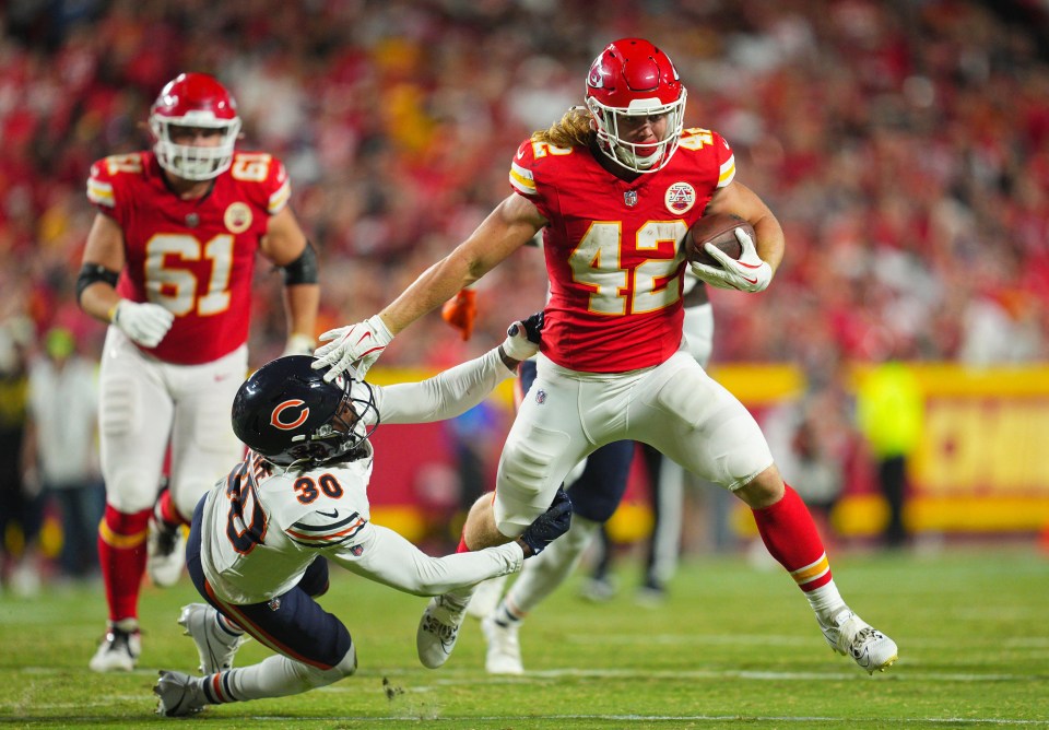 Kansas City Chiefs running back carrying the ball, being tackled by a Chicago Bears player.