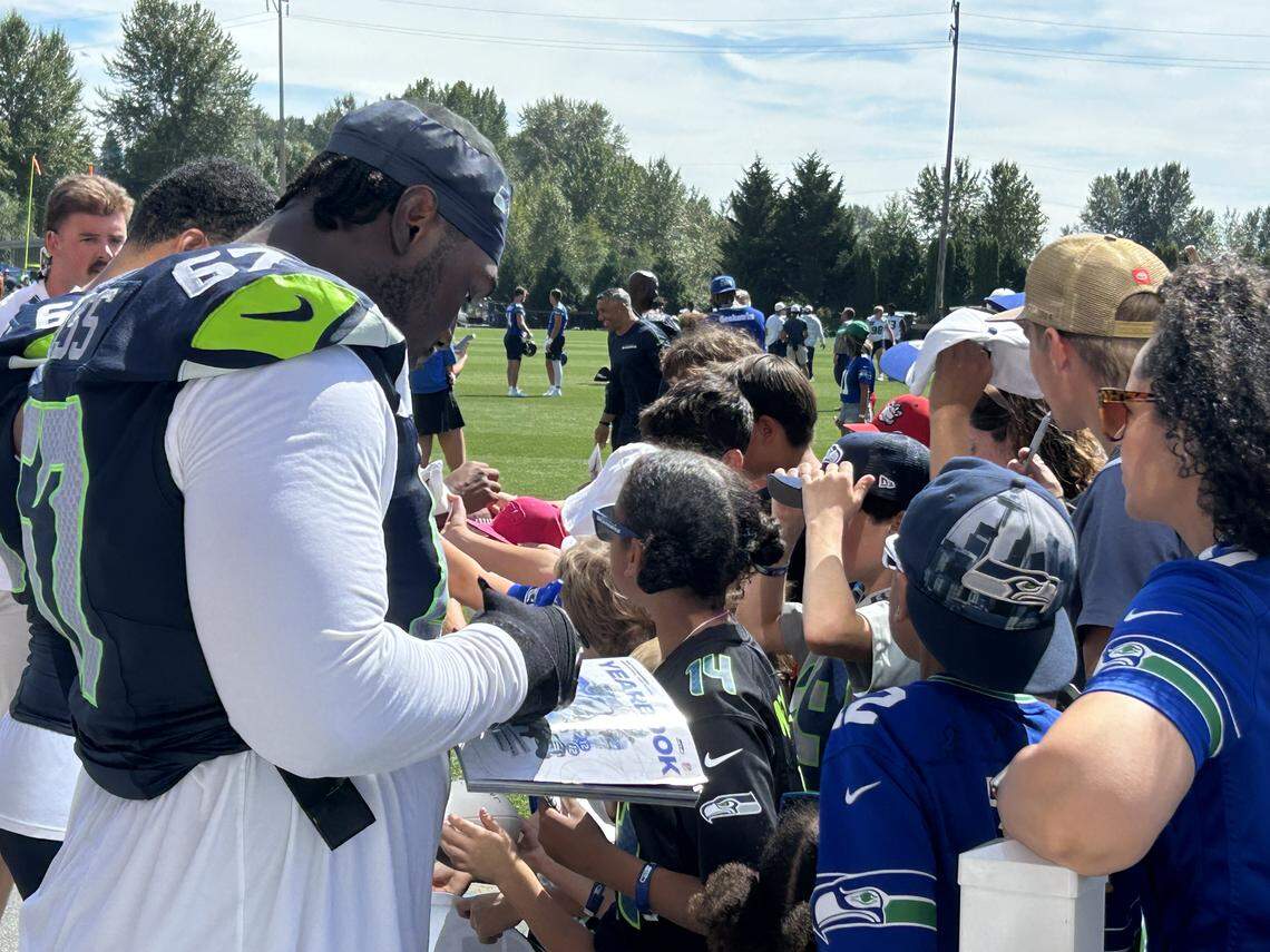 Seahawks left tackle Charles Cross signs autographs for fans following the fourth practice of Seattle&#x002019;s NFL training camp Saturday, July 26, 2025, at the Virginia Mason Athletic Center in Renton.