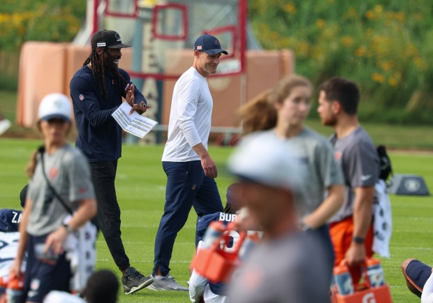 Chicago Bears defensive backs coach Al Harris, left, jokes with head coach Ben Johnson as players stretch out at training camp on July 28, 2025, in Lake Forest. (Stacey Wescott/Chicago Tribune)
