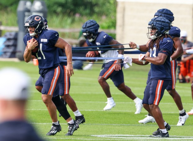 Chicago Bears running backs including Travis Homer (21) and Ian Wheeler (33) in the foreground, run through drills during training camp on July 28, 2025, in Lake Forest. (Stacey Wescott/Chicago Tribune)