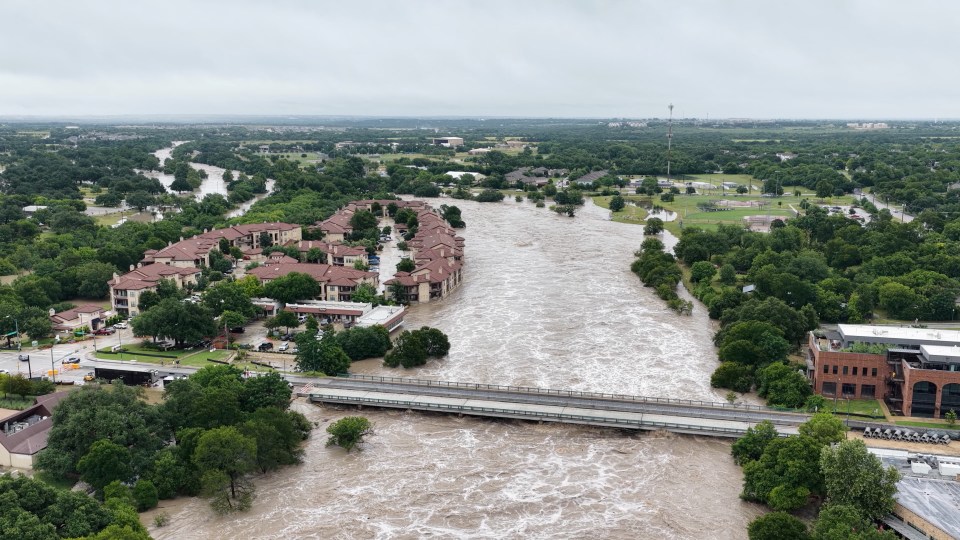 Aerial view of a flooded river in Georgetown, Texas, with buildings partially submerged.