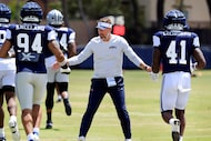 Dallas Cowboys head coach Brian Schottenheimer slaps hands with defensive ends Marshawn...