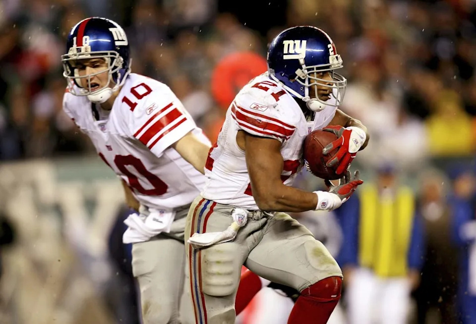 PHILADELPHIA - JANUARY 07: Quarterback Eli Manning #10 of the New York Giants hands the ball off to Tiki Barber #21 against the Philadelphia Eagles during their NFC Wildcard Playoff game on January 7, 2007 at Lincoln Financial Field in Philadelphia, Pennsylvania. (Photo by Doug Benc/Getty Images)