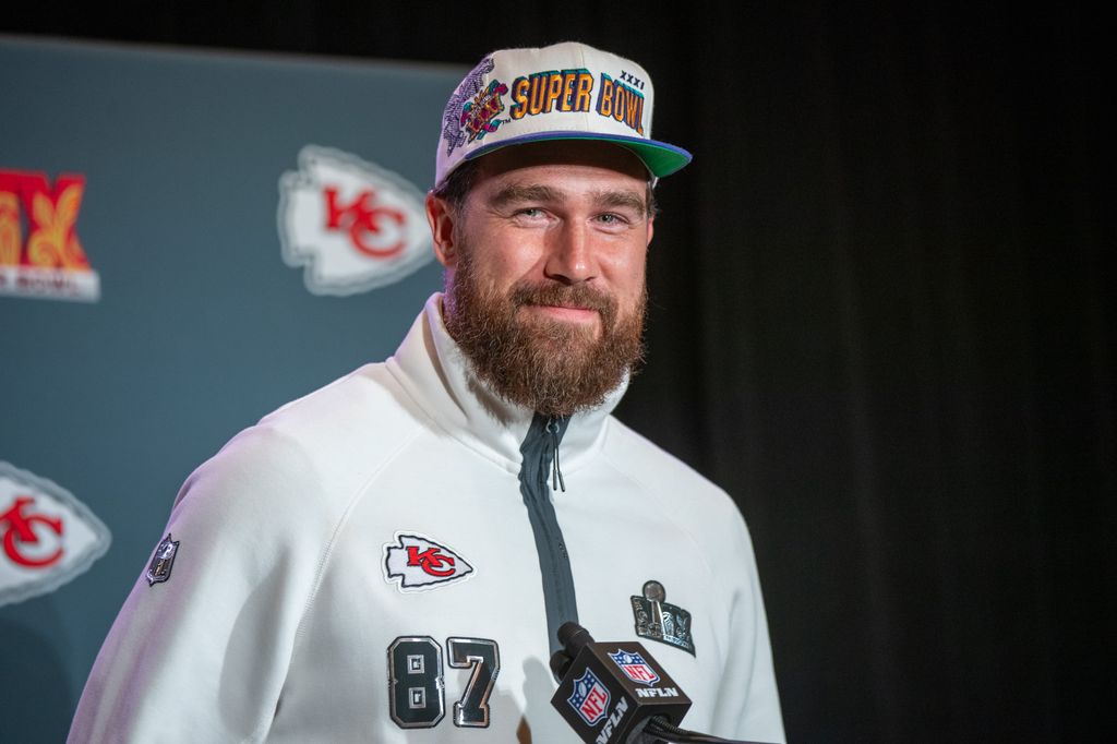 travis kelce wearing ballcap and smiling during press conference