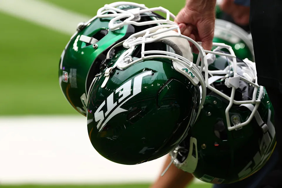 New York Jets helmets are held by staff.