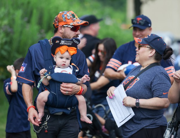 Dominic Pechacek and his 9-month-old-daughter, Lucia Pechacek, arrive at Chicago Bears training camp at Halas Hall on July 29, 2025, in Lake Forest.  Pechacek said his favorite player is D.J. Moore and he's happy they have a long term contract with him.  Pechacek said, "He's a phenomenal player and a good person toodoes a lot for the community." (Stacey Wescott/Chicago Tribune)