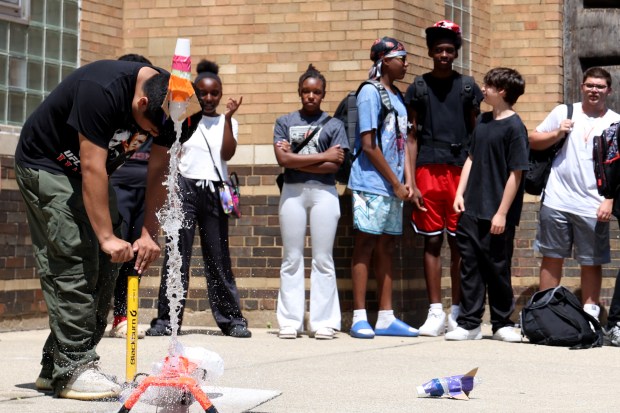 Staff member Julian Ascencio pumps and launches a water-propelled rocket as youths look on outside the Bartlett J. McCartin Boys & Girls Club on Friday, July 18, 2025. The Boys & Girls Clubs of Chicago teamed up with Moore's Moore2Life Foundation to host a Back to School bash in celebration of local youth. (Antonio Perez/Chicago Tribune)