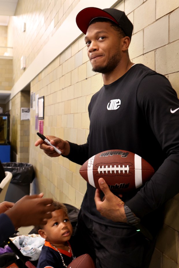 Bears receiver DJ Moore, with son Bubba, 2, autographs a football at the Bartlett J. McCartin Boys & Girls Club on Friday, July 18, 2025. The Boys & Girls Clubs of Chicago teamed up with Moore's Moore2Life Foundation to host a Back-to-School Bash in celebration of local youth. (Antonio Perez/Chicago Tribune)