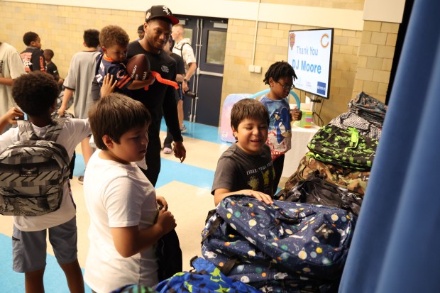 Bears receiver DJ Moore, holding son Bubba, 2, gives out free backpacks to youths at the Chicago Boys and Girls Clubs of Chicago's Bartlett J. McCartin Club on Friday, July 18, 2025. The Boys and Girls Clubs of Chicago teamed up with Moore's Moore2Life Foundation to host a Back to School bash in celebration of local youth. (Antonio Perez/Chicago Tribune)