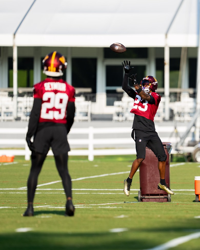 Cornerback Kevin Seymour watches as cornerback Trey Amos catches a ball during camp drills. (Abdullah Konte/The Washington Informer)