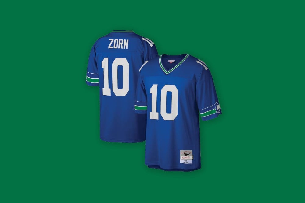Front and back views of the Jim Zorn Seattle Seahawks Mitchell & Ness Legacy Replica Jersey in bright blue against a green background.