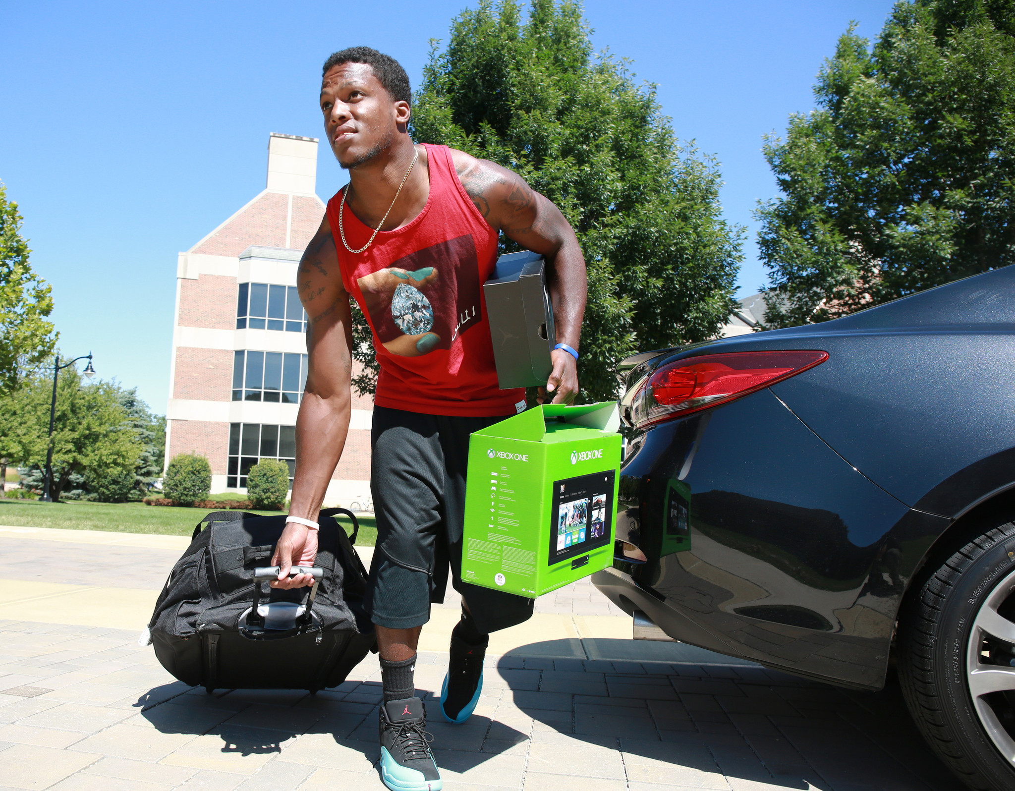 C. J. Wilson carries shoes, a game console and luggage as he arrives at Bears training camp.