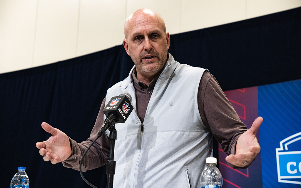 Man speaking at a podium with an NFL microphone.