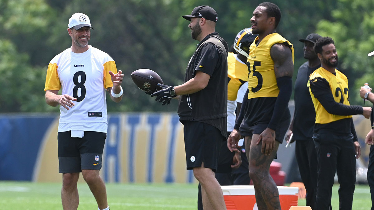Steelers quarterback Aaron Rodgers (8) drops back to pass during minicamp at their South Side facility with Steelers head coach Mike Tomlin in the background