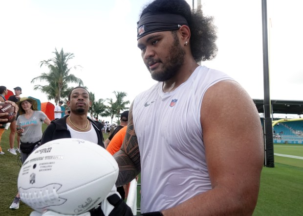 Miami Dolphins guard Jonah Savaiinaea (72) greets fans during practice...