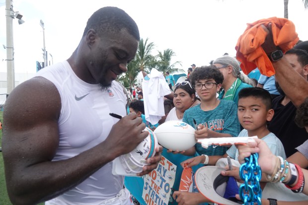 Miami Dolphins linebacker Eugene Asante (51) signs for fans during...