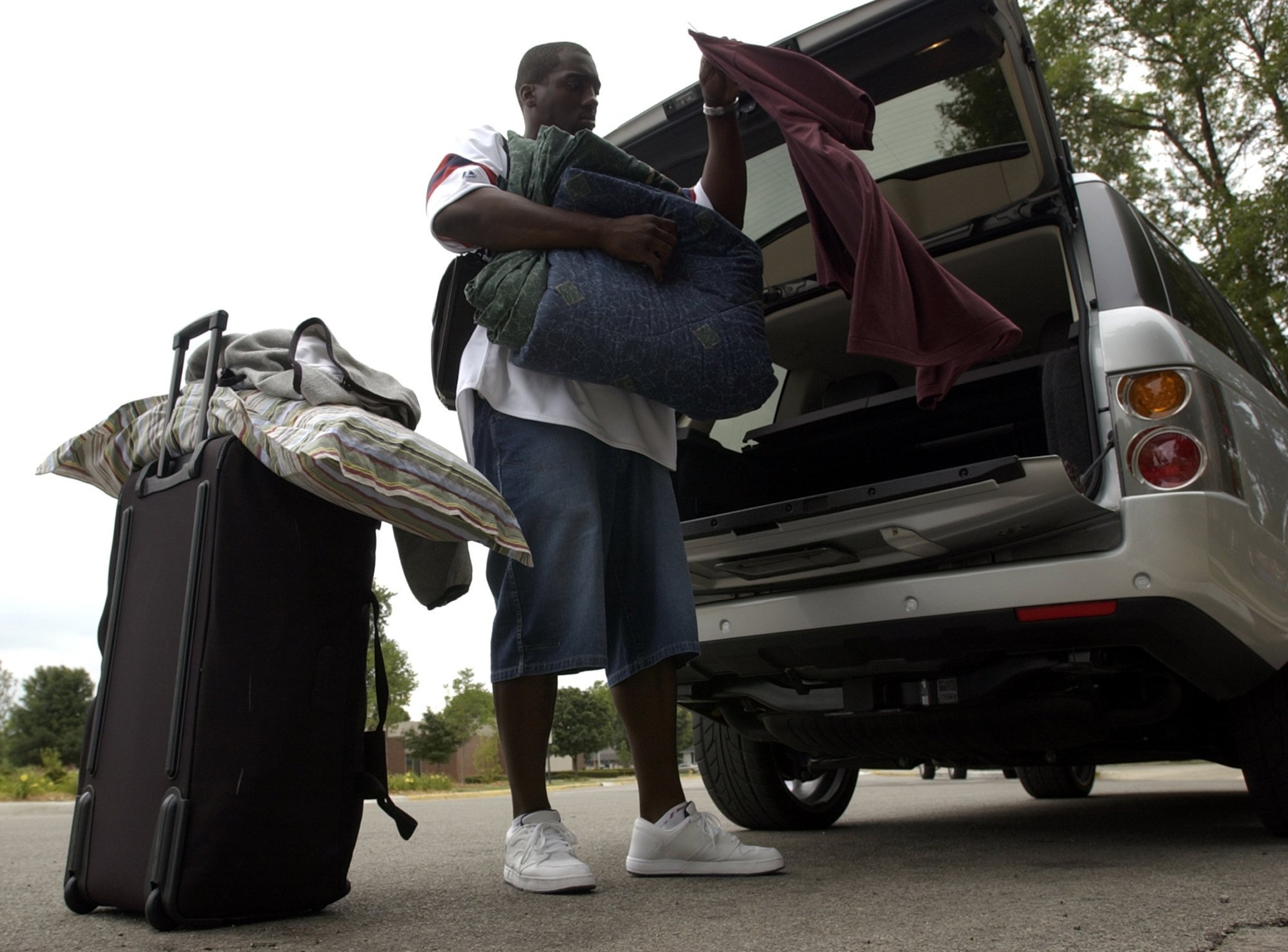 Linebacker Rosevelt Colvin unloads his belongings from his Range Rover after arriving in 2002.