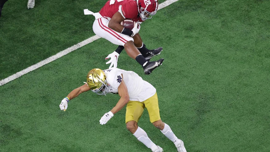 ARLINGTON, TEXAS – JANUARY 01: Running back Najee Harris #22 of the Alabama Crimson Tide leaps cornerback Nick McCloud #4 of the Notre Dame Fighting Irish during the first quarter of the 2021 College Football Playoff Semifinal Game at the Rose Bowl Game presented by Capital One at AT&T Stadium on January 01, 2021 in Arlington, Texas. (Photo by Carmen Mandato/Getty Images)