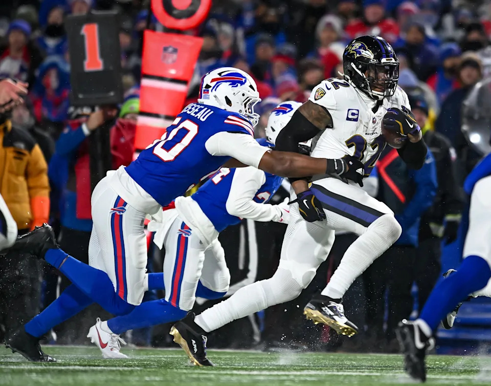 Jan 19, 2025; Orchard Park, New York, USA; Baltimore Ravens running back Derrick Henry (22) carries the ball as Buffalo Bills defensive end Greg Rousseau (50) attempts a tackle in the third quarter of a 2025 AFC divisional round game at Highmark Stadium. Mandatory Credit: Mark Konezny-Imagn Images