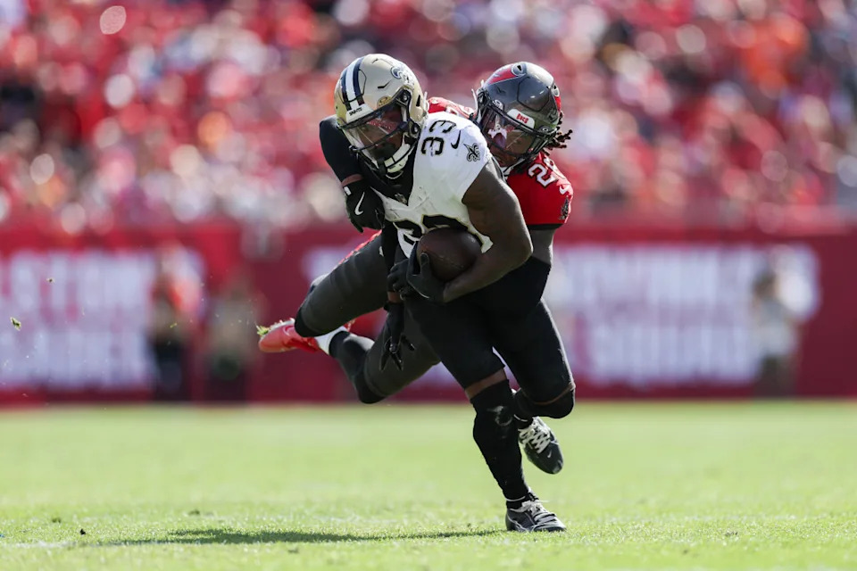 Jan 5, 2025; Tampa, Florida, USA; New Orleans Saints running back Jordan Mims (33) is brought down by Tampa Bay Buccaneers cornerback Dallis Flowers (28) in the second quarter at Raymond James Stadium. Mandatory Credit: Nathan Ray Seebeck-Imagn Images
