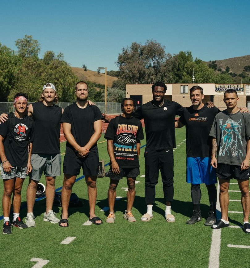 Group photo of eight men on a track and field.