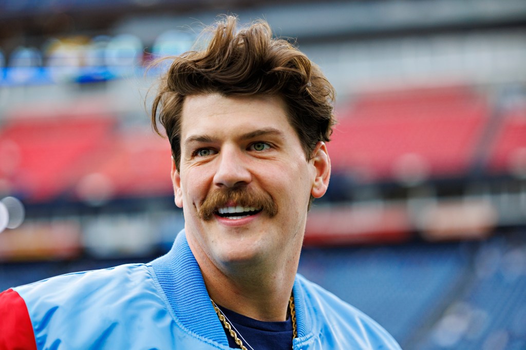 Close-up of a man with a mustache, smiling.