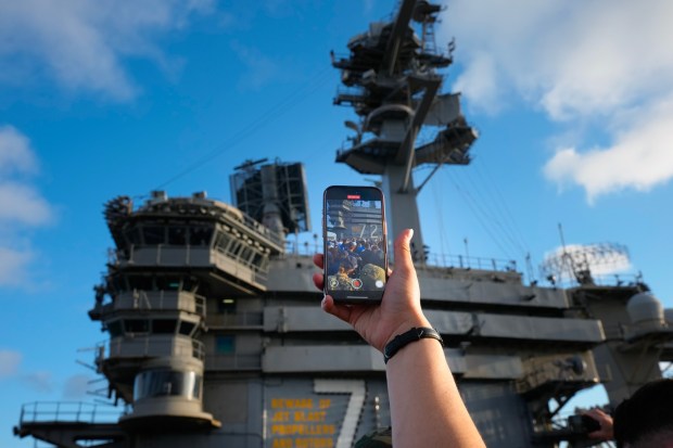 A sailor holds her phone up high to video record the LA Chargers on the flight deck of the USS Abraham Lincoln (CVN 72).  (Nelvin C. Cepeda / The San Diego Union-Tribune)
