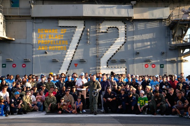 Crew members from the USS Abraham Lincoln (CVN 72), along with the LA Chargers, take a group photo on the flight deck. (Nelvin C. Cepeda / The San Diego Union-Tribune)