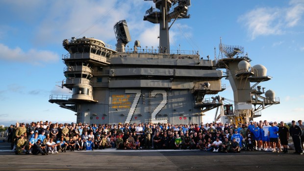 Crew members from the USS Abraham Lincoln (CVN 72), along with the LA Chargers, take a group photo on the flight deck. (Nelvin C. Cepeda / The San Diego Union-Tribune)