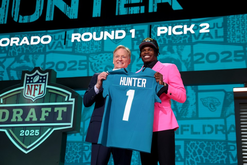 Travis Hunter holding his Jacksonville Jaguars jersey at the 2025 NFL Draft.