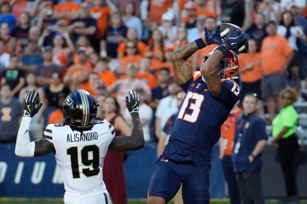 Illinois wide receiver Pat Bryant catches a touchdown pass from quarterback Luke Altmyer as Purdue defensive back Botros Alisandro defends during the overtime period of an NCAA college football game Saturday, Oct. 12, 2024, in Champaign, Ill. Illinois won 50-49. (AP Photo/Charles Rex Arbogast)